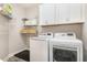 Well-organized laundry room with white washer and dryer, overhead cabinets, and wire shelving at 1001 Peterson Ridge Rd, Fuquay Varina, NC 27526