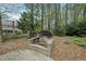 Backyard brick fire pit and seating area surrounded by trees providing a cozy outdoor gathering space at 1007 Surry Dale Ct, Apex, NC 27502