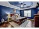Luxurious bedroom suite with a blue tray ceiling, wooden accents, and lots of natural light at 1056 Lukestone Dr, Fuquay Varina, NC 27526