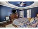 Spacious Primary bedroom features a tray ceiling, hardwood floors, TV, and abundant natural light at 1056 Lukestone Dr, Fuquay Varina, NC 27526