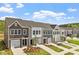 Row of townhomes featuring gray and white exteriors, well-kept lawns, and individual driveways under a sunny sky at 120 Central Townes Way # 292, Raleigh, NC 27603