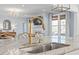 Kitchen island featuring gray and white granite countertops and stainless steel sink, overlooking the living room at 126 Filigree Way, Durham, NC 27713