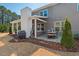 Covered outdoor patio with grill, white fireplace, patio table, and string lights for cozy atmosphere at 126 Filigree Way, Durham, NC 27713