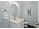 Stylish powder room with patterned wallpaper, an oval mirror, and gold accents at 126 Filigree Way, Durham, NC 27713