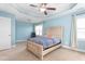 Bright main bedroom with neutral carpet, tray ceiling, and ceiling fan at 130 Campaign Dr, Mebane, NC 27302