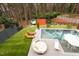 A backyard with a pool, chairs, lounge chairs, trampoline, a sport court, and lush green landscaping at 1323 Ridge Rd, Raleigh, NC 27607