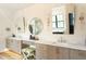 Bright bathroom featuring double sinks, stylish mirrors, zebra ottoman, and wooden cabinets at 1323 Ridge Rd, Raleigh, NC 27607