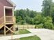 Exterior of the home with stairs to the porch and a fenced-in yard with trees in the background at 1448C Maplewood Dr, Durham, NC 27704