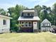 A small home with craftsman trim, a metal roof and a neatly manicured lawn is nestled in a wooded lot at 1448C Maplewood Dr, Durham, NC 27704