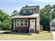 A small home with craftsman trim, a metal roof and a neatly manicured lawn is nestled in a wooded lot at 1448C Maplewood Dr, Durham, NC 27704
