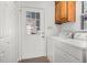 Bright laundry room featuring a washer, dryer, wood cabinets, and an exterior glass paneled door at 1709 Shamrock Ln, Rocky Mount, NC 27804