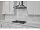Close-up of a modern kitchen with stainless range hood, white subway tile backsplash and white countertops at 1776 Golden Honey Dr, Wake Forest, NC 27587
