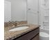 Bathroom with granite vanity top, dark wood cabinets, a framed mirror, and a white tub and shower at 2105 Attend Xing, Fuquay Varina, NC 27526