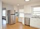 Well-lit kitchen featuring stainless steel appliances, white cabinets, and vinyl floors at 215 Sallinger St, Knightdale, NC 27545