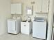 Bright laundry room with white washer, dryer, sink and storage cabinets at 215 Sallinger St, Knightdale, NC 27545