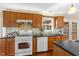 Well-lit kitchen featuring wood cabinets, dark countertops, and stainless steel appliances at 2732 Beehnon Way, Raleigh, NC 27603