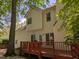 Two-story beige home featuring a spacious red deck, set amidst a lush, green landscape at 3109 Benton Cir, Raleigh, NC 27615