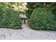 Exterior view of a home's entrance, framed by lush green bushes and a gravel walkway at 3601 Swann St, Raleigh, NC 27612