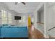 Bright living room with hardwood floors, blue sofa, TV and entry to stairway and yellow door at 3741 Manly Farm Rd, Wake Forest, NC 27587
