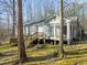 View of home's rear exterior highlighting the deck and sunroom, all set within a serene, wooded landscape at 405 Lookout Pt, Rougemont, NC 27572