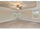 Bright bedroom featuring neutral walls, a trey ceiling with fan, and multiple windows offering abundant natural light at 6712 Stepherly Way, Holly Springs, NC 27540