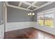 Elegant dining room featuring hardwood floors, wainscoting, trey ceiling, and modern lighting fixture at 6712 Stepherly Way, Holly Springs, NC 27540