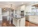 Open kitchen with white cabinets, stainless appliances, and a granite island flowing into a living space with trey ceilings at 6712 Stepherly Way, Holly Springs, NC 27540