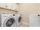 Bright laundry room featuring a washer, dryer, and overhead cabinets at 6712 Stepherly Way, Holly Springs, NC 27540