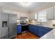 Updated kitchen features stainless steel appliances, white subway tile backsplash, and custom blue cabinets at 8617 Canoe Ct, Raleigh, NC 27615