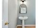 Cozy half bathroom with a pedestal sink, vintage mirror and sconce lighting at 1013 Traders Trl, Wake Forest, NC 27587