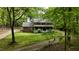 Two-story brick home with a white porch, surrounded by lush trees and a winding driveway on a sunny day at 1013 Traders Trl, Wake Forest, NC 27587