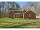 Backyard view of a brick home featuring a lush lawn surrounded by mature trees in a serene setting at 1013 Traders Trl, Wake Forest, NC 27587