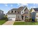 Charming two-story home boasts a mix of stone, brick, and siding with a two-car garage and lush front lawn at 112 Ava Ct, Holly Springs, NC 27540