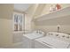 Bright laundry room features modern machines, window, and shelf storage, offering convenience and functionality at 113 Preston Pines Dr, Cary, NC 27513