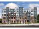 A modern townhome complex showcasing brick facades, stylish accents, and rooftop terraces under a partly cloudy sky at 1257 S Blount Street # 201, Raleigh, NC 27601