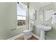 Compact powder room featuring a pedestal sink, round mirror, and a window providing natural light and views at 1257 S Blount Street # 201, Raleigh, NC 27601