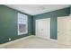 Bedroom featuring green walls, neutral carpet, and white trim, with a window and closet at 127 Plano Dr, Durham, NC 27703