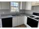 Bright kitchen featuring white cabinets, granite countertops, and modern black appliances at 128 Glengariff Ln, Clayton, NC 27520