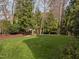 Large backyard with lush green grass, mature trees, and a partial border fence at 13121 Sargas St, Raleigh, NC 27614