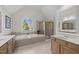 Bright bathroom featuring double vanity, large tub with tile surround and large arched window at 13121 Sargas St, Raleigh, NC 27614