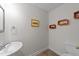 Half bath featuring a pedestal sink, toilet, flooring, and colorful framed car prints at 13121 Sargas St, Raleigh, NC 27614