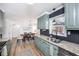 Bright kitchen featuring light green cabinetry, granite counters and stainless steel sink and black backsplash and view to dining area at 1617 Jenkins Rd, Wake Forest, NC 27587