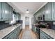 Galley kitchen with light green cabinets, granite countertops, stainless steel appliances, and black backsplash at 1617 Jenkins Rd, Wake Forest, NC 27587
