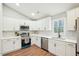 Close-up of the bright kitchen showcasing the stainless steel appliances, white cabinets, and hard wood floors at 1911 Stadium Dr, Durham, NC 27705