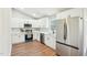 Bright kitchen featuring white cabinets, stainless steel appliances, tile backsplash, and hardwood floors at 1911 Stadium Dr, Durham, NC 27705