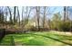 Large grassy backyard featuring an iron fence, lush landscaping and mature trees at 206 Pine St, Fuquay Varina, NC 27526