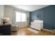 Charming Bedroom with paneled accent wall, hardwood floors, white crib, and comfortable chair at 206 Pine St, Fuquay Varina, NC 27526