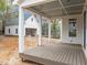 Covered back porch with wood flooring and classic white columns, perfect for outdoor living and entertaining at 207 Holleman St, Apex, NC 27502