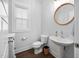Bright powder room features a pedestal sink, modern fixtures, and a round mirror, exuding understated elegance at 2404 Glade Mill Ct, Fuquay Varina, NC 27526