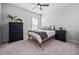Bedroom featuring carpet, a ceiling fan, and a bed with brown wood frame and black wooden dresser at 2404 Glade Mill Ct, Fuquay Varina, NC 27526
